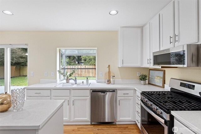 kitchen featuring light countertops, recessed lighting, appliances with stainless steel finishes, white cabinetry, and a sink