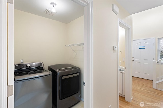 laundry room featuring visible vents, light wood-style flooring, laundry area, and washer and clothes dryer