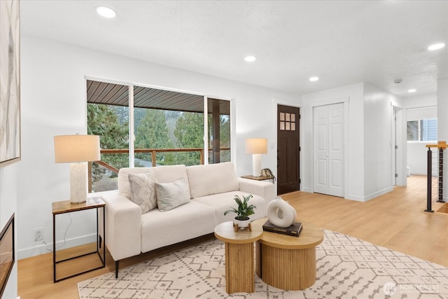 living room with recessed lighting, baseboards, and light wood-style floors