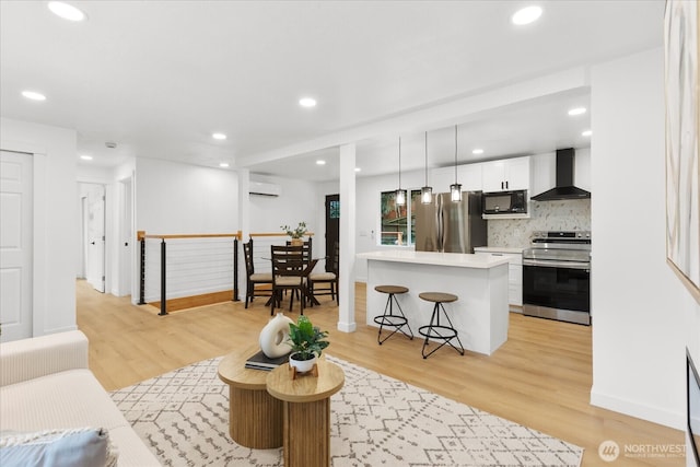 living area with an AC wall unit, light wood-style flooring, and recessed lighting