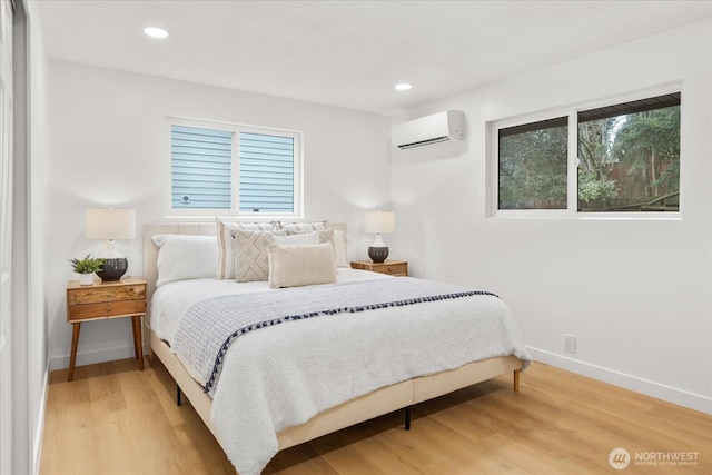 bedroom featuring recessed lighting, a wall mounted air conditioner, baseboards, and wood finished floors