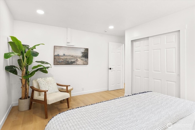 bedroom with recessed lighting, light wood-type flooring, baseboards, and a closet