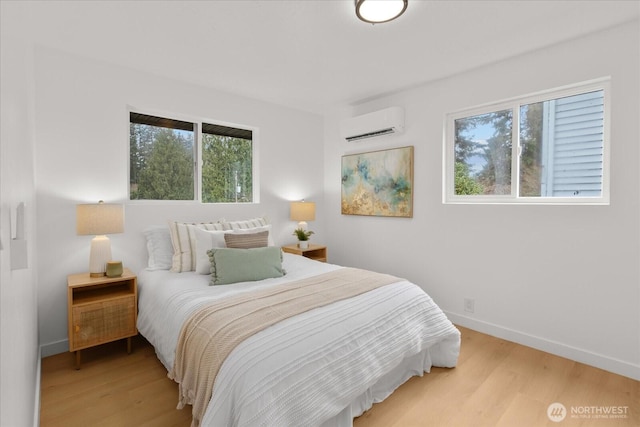 bedroom featuring light wood-style flooring, a wall mounted AC, and baseboards