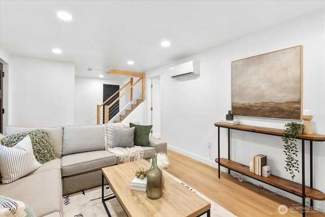 living area featuring a wall mounted air conditioner, light wood-style flooring, recessed lighting, baseboards, and stairs