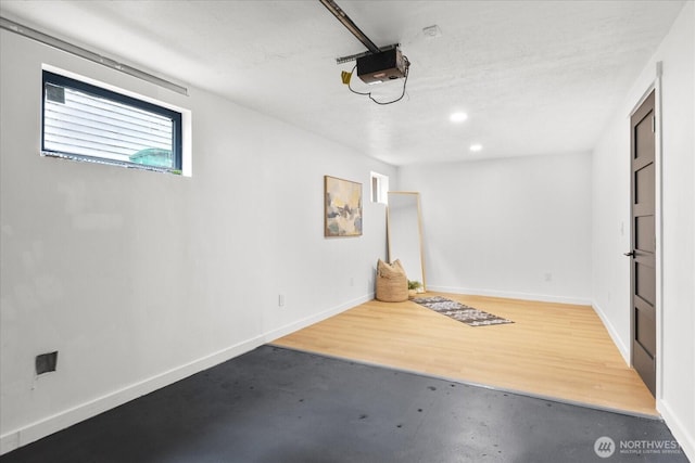 garage featuring recessed lighting, a garage door opener, and baseboards