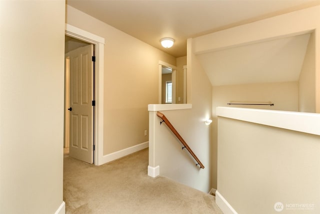 hall with an upstairs landing, carpet flooring, and baseboards