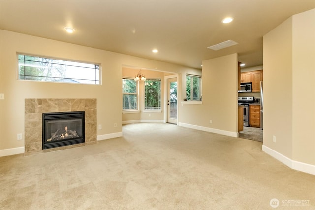 unfurnished living room featuring a tiled fireplace, light colored carpet, and baseboards