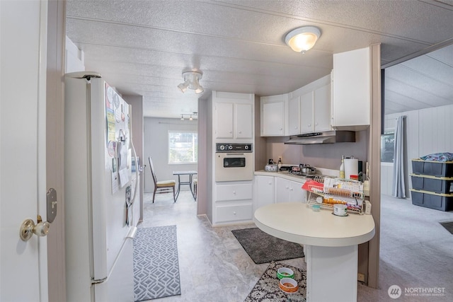 kitchen with white cabinetry, white appliances, light countertops, and under cabinet range hood