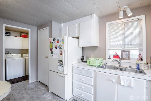 kitchen featuring a sink, white cabinetry, freestanding refrigerator, separate washer and dryer, and light countertops