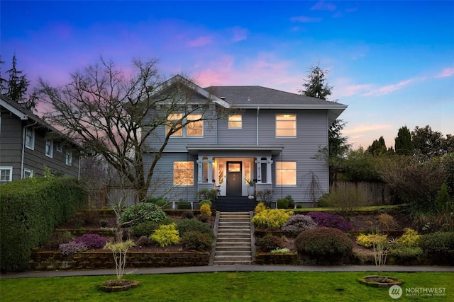 view of front of house featuring stairway and a yard