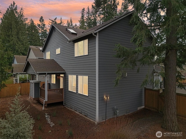 view of home's exterior with a shingled roof, a wooden deck, fence, and crawl space