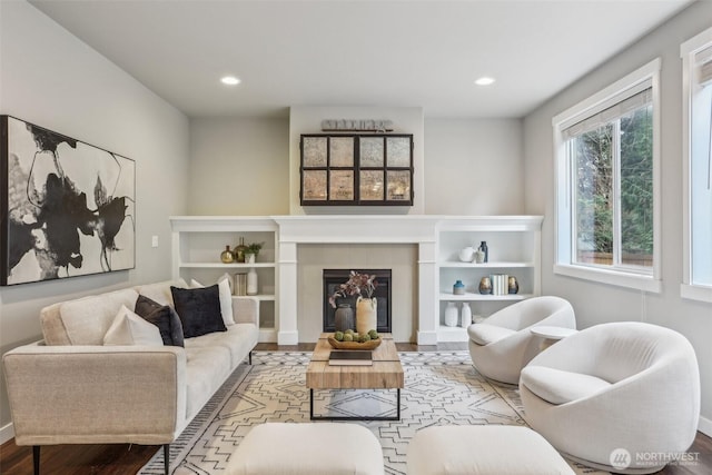 living room with a tiled fireplace, recessed lighting, and wood finished floors