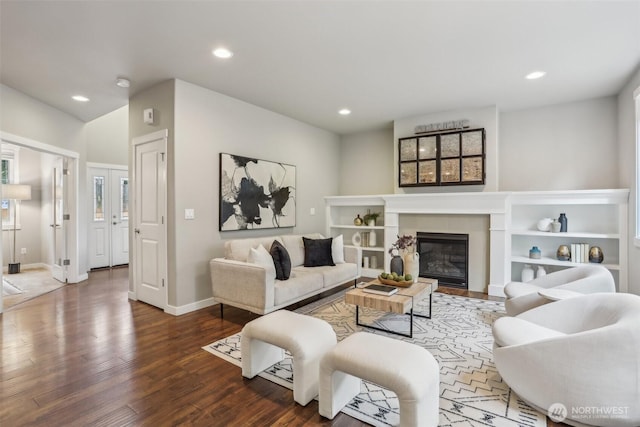 living area featuring a glass covered fireplace, recessed lighting, baseboards, and wood finished floors