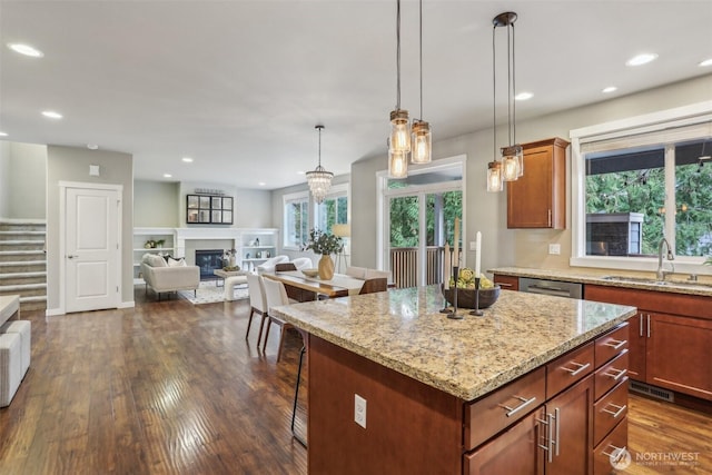 kitchen with a sink, a kitchen breakfast bar, a glass covered fireplace, and open floor plan