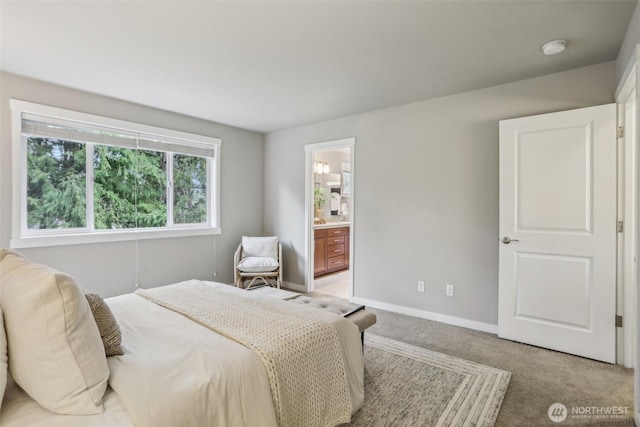 bedroom with ensuite bath, light colored carpet, and baseboards