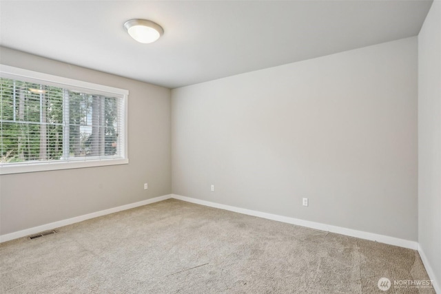 empty room featuring carpet, visible vents, and baseboards