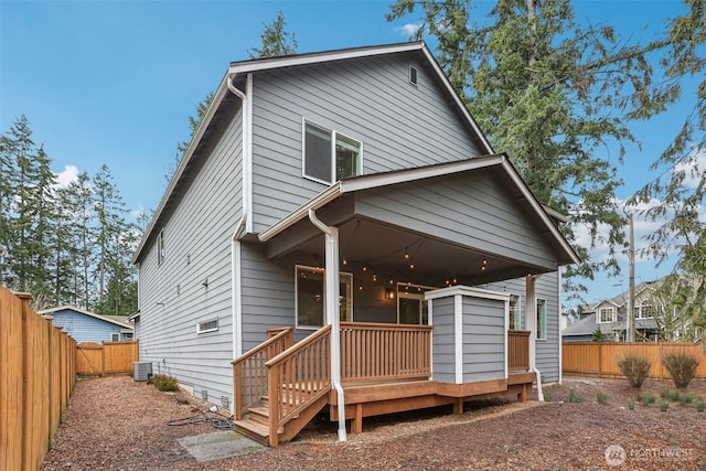 back of house featuring a fenced backyard and central AC