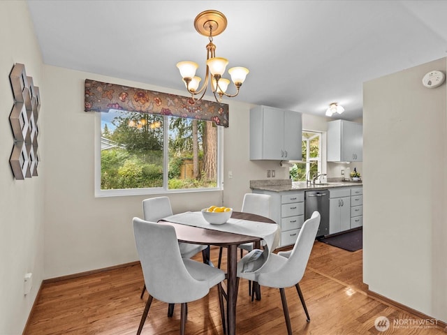 dining room with baseboards, an inviting chandelier, and light wood finished floors