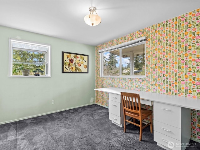 unfurnished office featuring baseboards, dark colored carpet, and built in study area