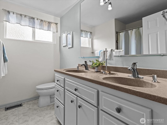 bathroom featuring a wealth of natural light, visible vents, toilet, and a sink