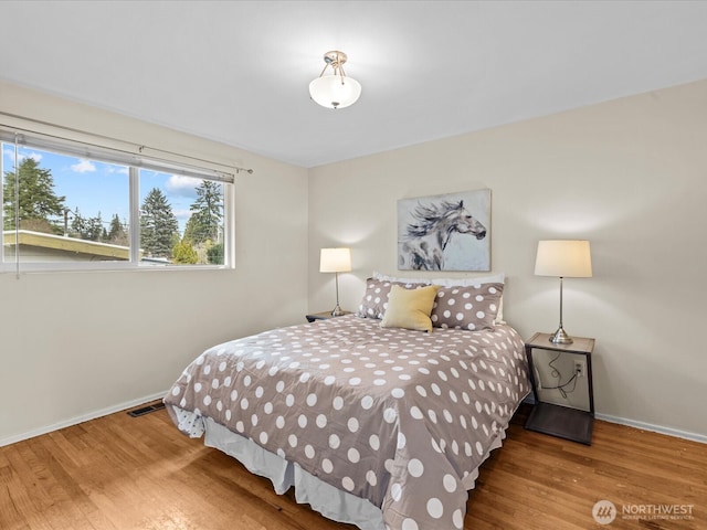 bedroom with visible vents, baseboards, and wood finished floors