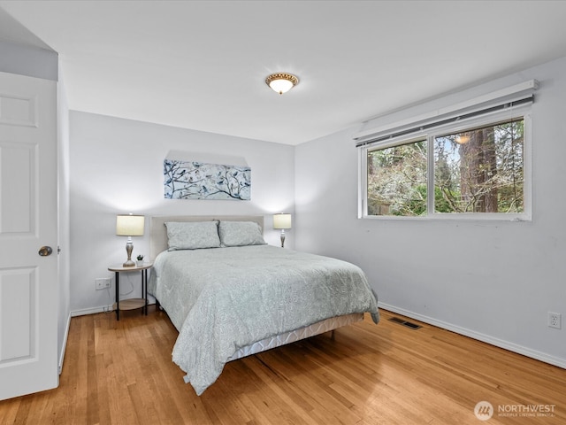 bedroom featuring visible vents, baseboards, and wood finished floors