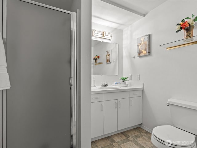 bathroom featuring a stall shower, toilet, vanity, and baseboards