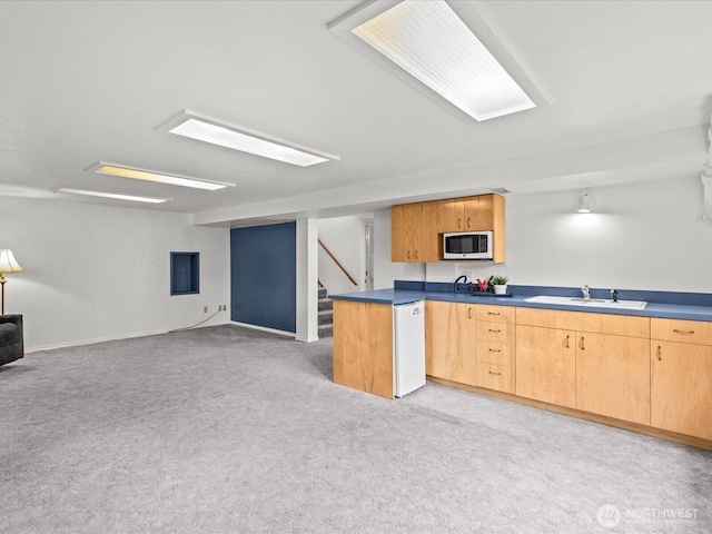 kitchen with light carpet, open floor plan, white appliances, and a sink