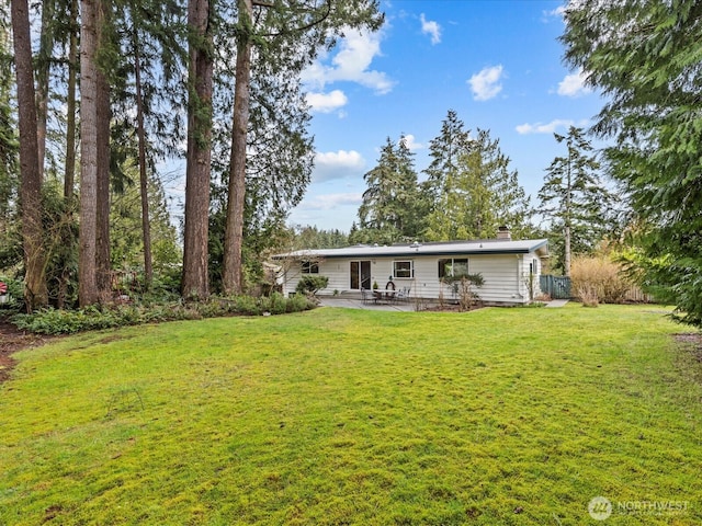 back of property featuring a patio, a yard, and a chimney