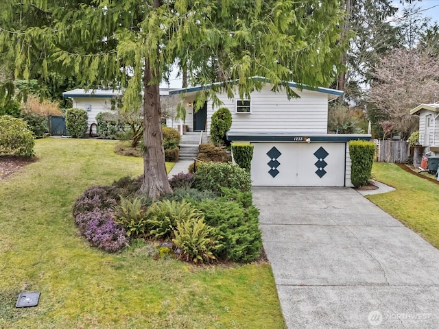 view of front of home featuring a garage, driveway, a front yard, and fence