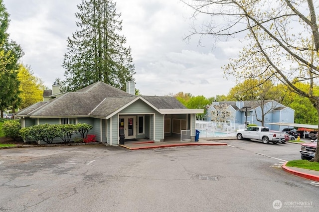 975 Aberdeen Ave NE Unit F407, Renton, WA 98056 - view of front of property with fence, uncovered parking, a shingled roof, a chimney, and french doors