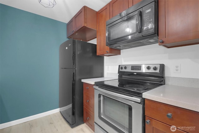 975 Aberdeen Ave NE Unit F407, Renton, WA 98056 - kitchen featuring black appliances, brown cabinetry, light wood finished floors, baseboards, and light countertops