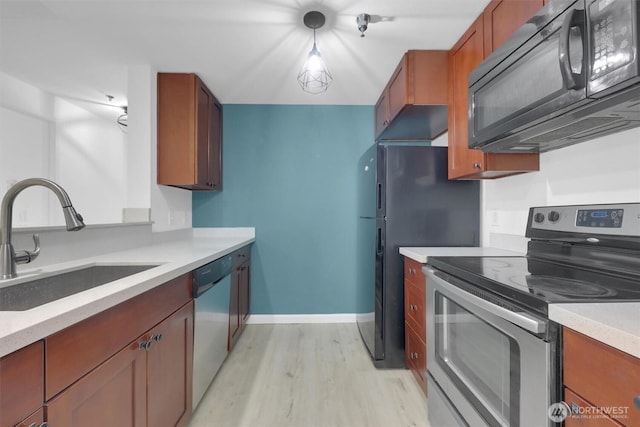 975 Aberdeen Ave NE Unit F407, Renton, WA 98056 - kitchen featuring baseboards, light wood finished floors, a sink, appliances with stainless steel finishes, and brown cabinets