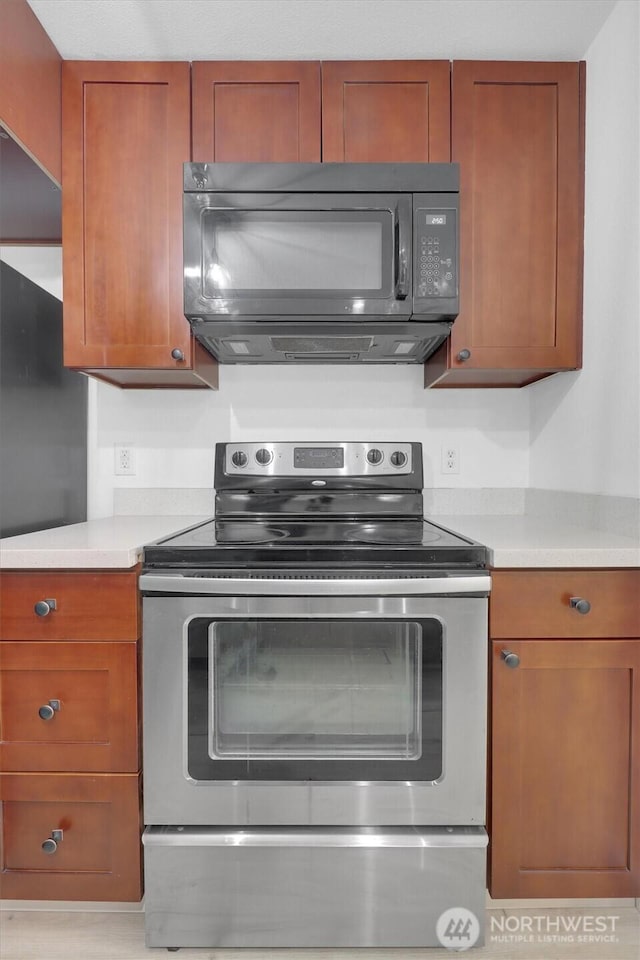 975 Aberdeen Ave NE Unit F407, Renton, WA 98056 - kitchen with electric range, brown cabinets, light countertops, and black microwave