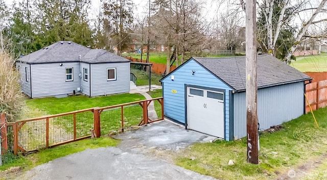 detached garage featuring driveway and fence