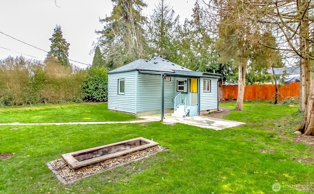 back of house with crawl space, a lawn, a shingled roof, and fence