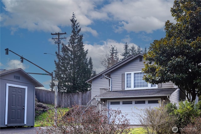 view of home's exterior featuring stairway, an attached garage, an outdoor structure, and fence