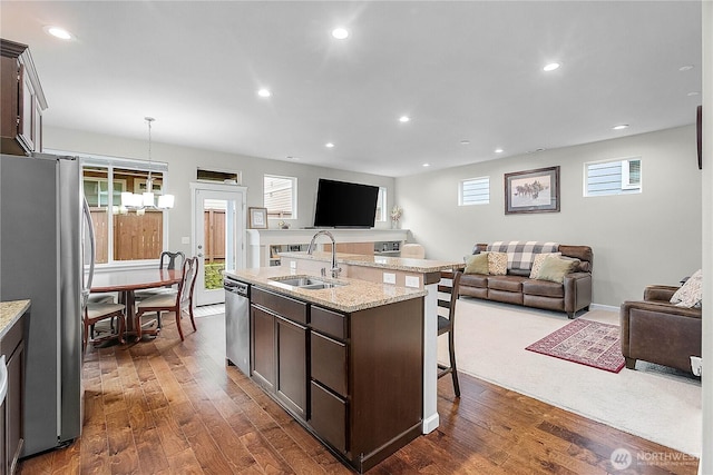 kitchen featuring dark brown cabinets, open floor plan, appliances with stainless steel finishes, and a sink