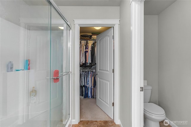 full bathroom featuring a shower stall, a spacious closet, and toilet