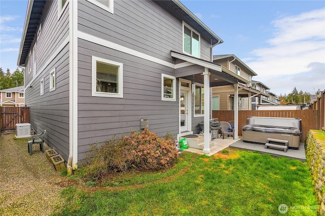 back of property with a patio area, a yard, a hot tub, and a fenced backyard