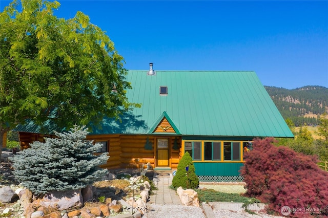 cabin with log exterior, metal roof, and a standing seam roof