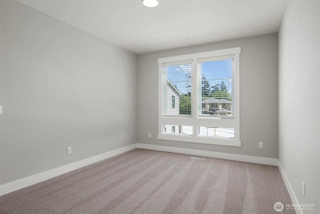 spare room with baseboards and light carpet