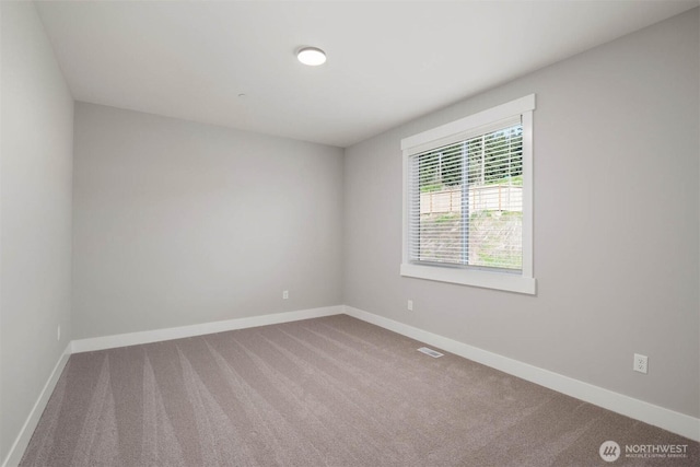 spare room featuring carpet flooring, baseboards, and visible vents