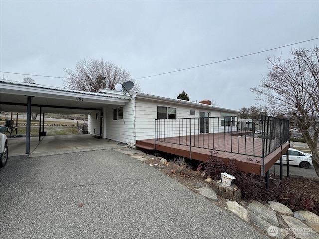 exterior space featuring an attached carport, driveway, and a wooden deck