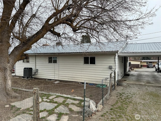 view of side of home with a carport, cooling unit, and metal roof