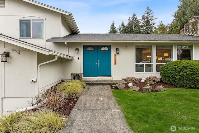 property entrance with a shingled roof and a yard