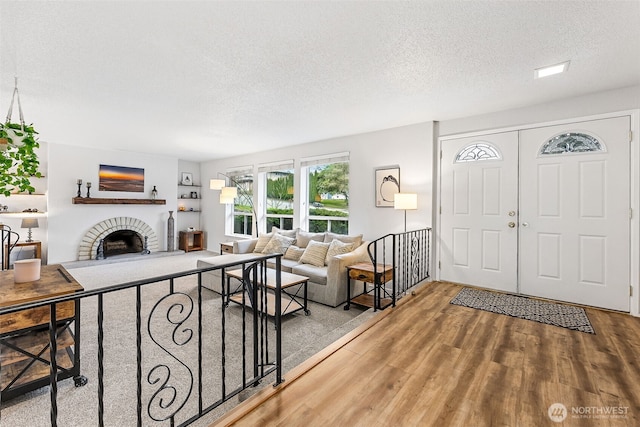 living room featuring a fireplace, a textured ceiling, and wood finished floors