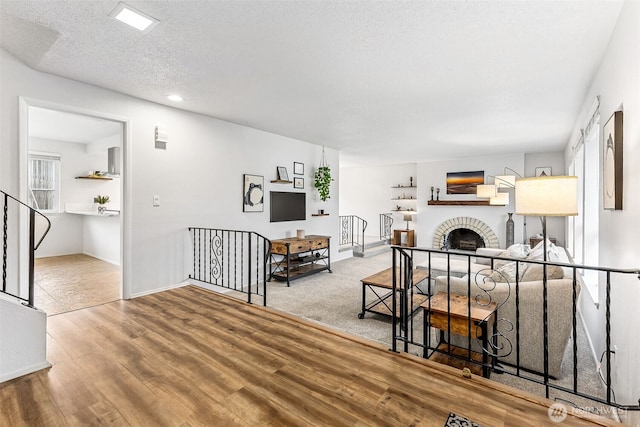 living area with baseboards, a textured ceiling, wood finished floors, and a fireplace