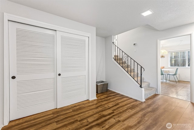 interior space with stairs, wood finished floors, baseboards, and a textured ceiling