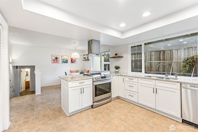 kitchen featuring a sink, appliances with stainless steel finishes, a peninsula, island range hood, and light stone countertops